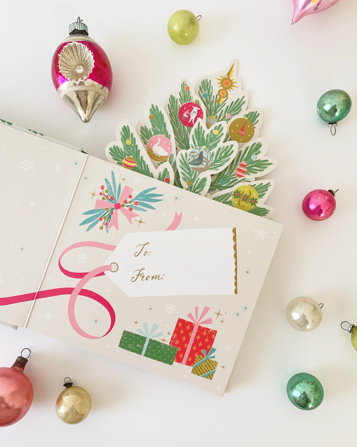 Inside cover of a holiday pop-up book surrounded by colorful ornaments on a white background