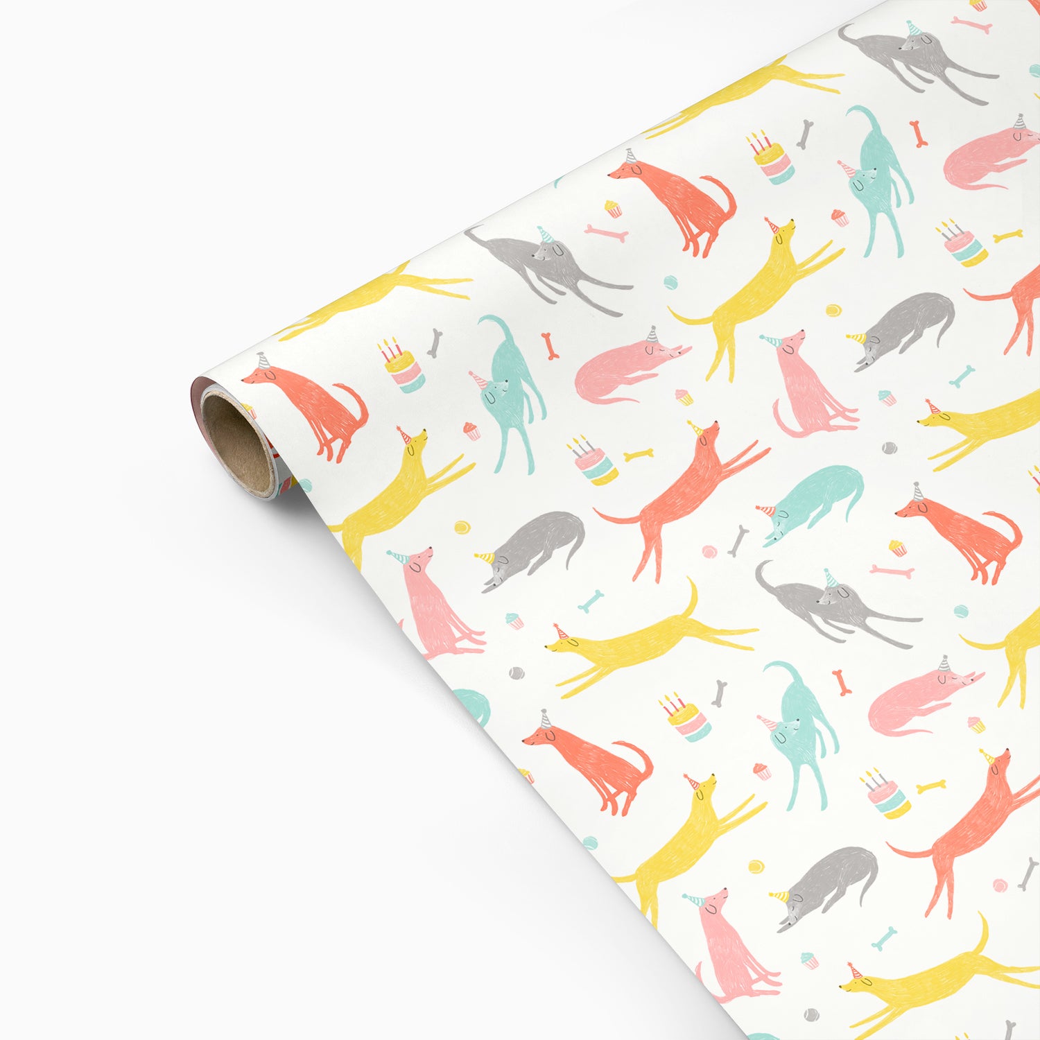 Roll of colorful dog patterned birthday wrapping paper on a white background
